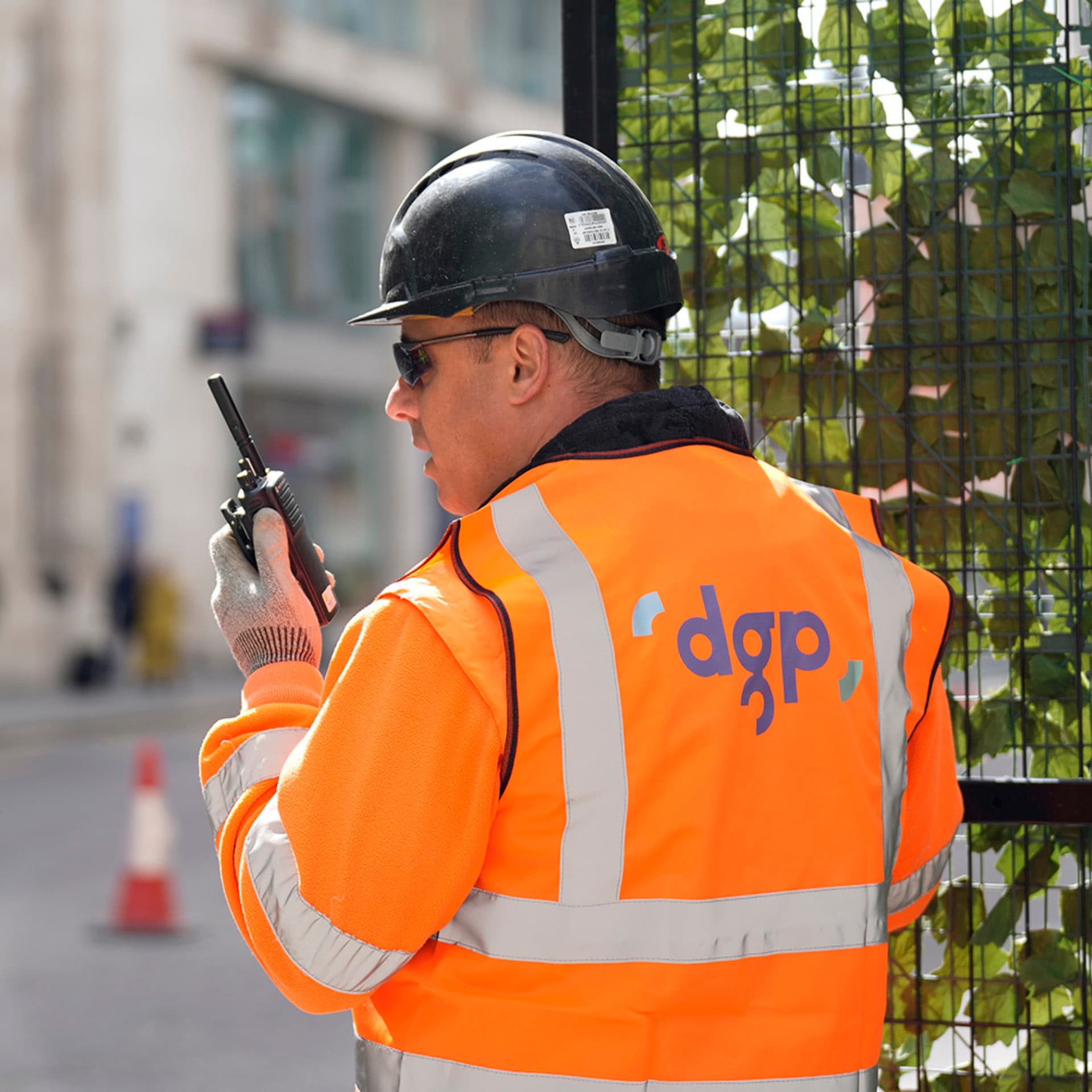A worker in a high visibility vest and hard hard on a walkie talkie